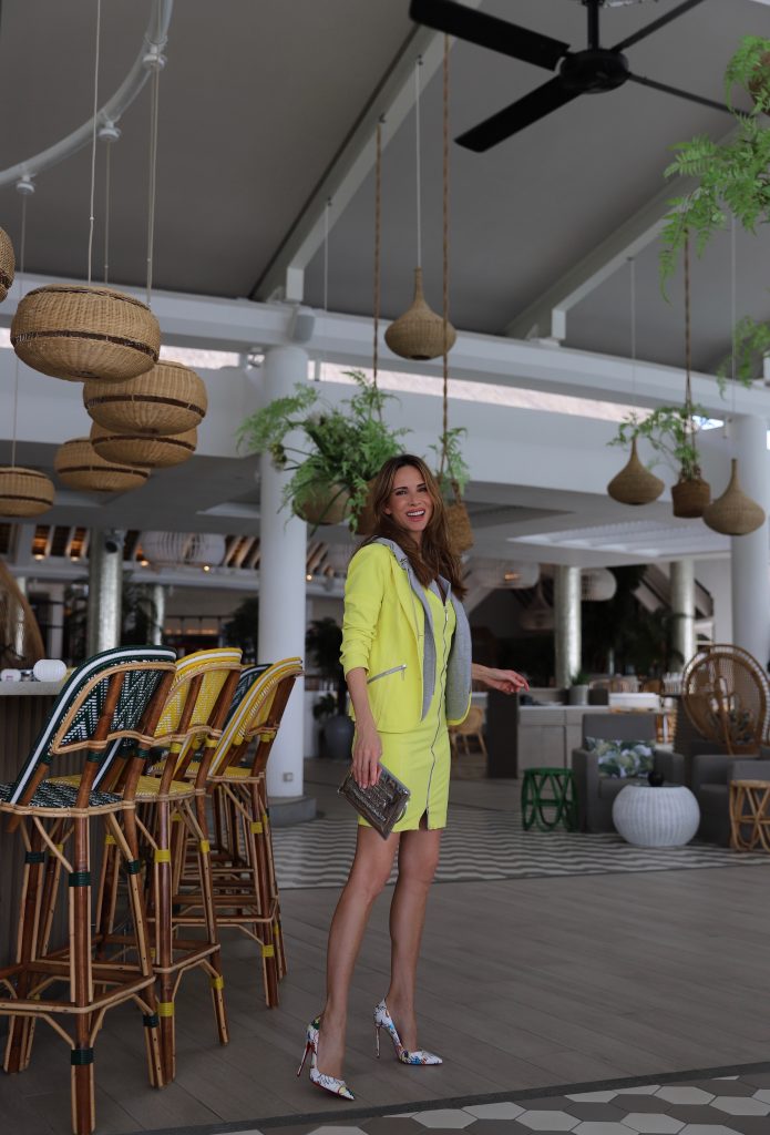 Alexandra Lapp in Yellow Mania wearing a yellow shift dress with zipper & a yellow como-blazer with hood, So Kate Loubitag red sole pumps with scribbled drawings, Louis Vuitton Monogram Miroir Pochette Plat Pouch and mirrored silver Aviator Le Specs seen on Mauritius during a press tour in April 2018.