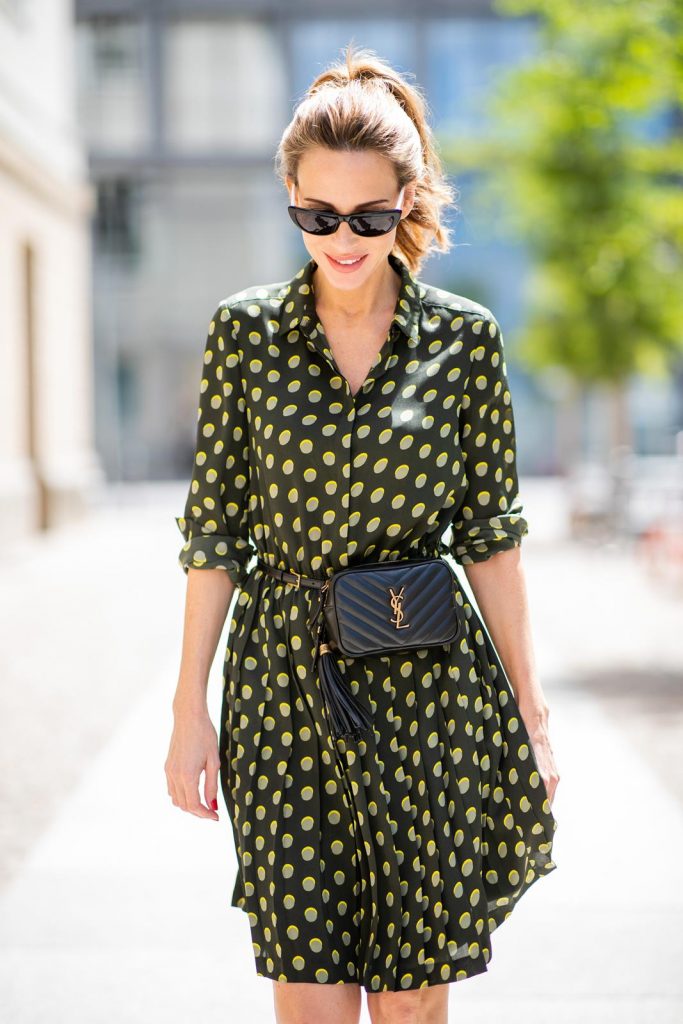 Steffen Schraut, Saint Laurent, Christian Louboutin, State Optical Co. Alexandra Lapp is seen in a Waist Belt Bag Look wearing a knee length dark green dress with green and yellow dots from Steffen Schraut, the Lou Belt Bag in black by Saint Laurent, the golden Iriza glitter pumps by Christian Louboutin and two tone sunglasses from State x Cotw in black white on July 13, 2018 in Berlin, Germany.