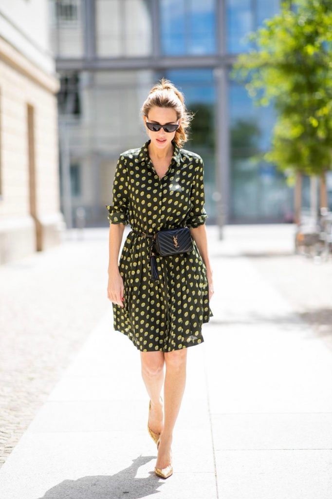 Steffen Schraut, Saint Laurent, Christian Louboutin, State Optical Co. Alexandra Lapp is seen in a Waist Belt Bag Look wearing a knee length dark green dress with green and yellow dots from Steffen Schraut, the Lou Belt Bag in black by Saint Laurent, the golden Iriza glitter pumps by Christian Louboutin and two tone sunglasses from State x Cotw in black white on July 13, 2018 in Berlin, Germany.