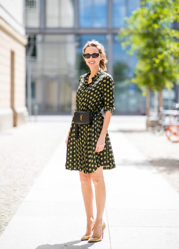 Steffen Schraut, Saint Laurent, Christian Louboutin, State Optical Co. Alexandra Lapp is seen in a Waist Belt Bag Look wearing a knee length dark green dress with green and yellow dots from Steffen Schraut, the Lou Belt Bag in black by Saint Laurent, the golden Iriza glitter pumps by Christian Louboutin and two tone sunglasses from State x Cotw in black white on July 13, 2018 in Berlin, Germany.