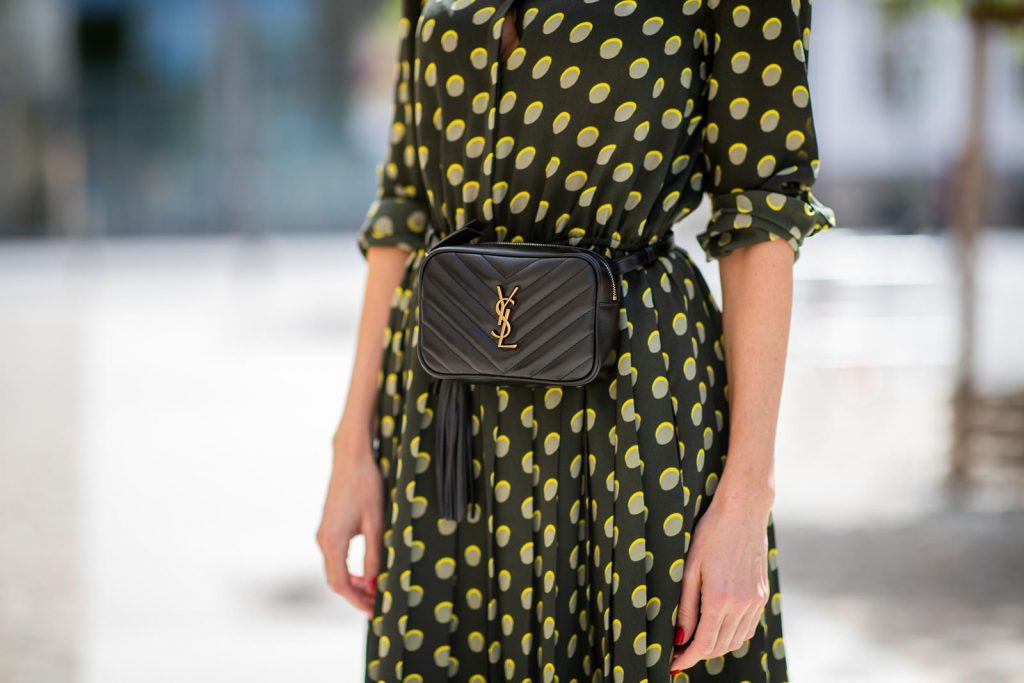 Steffen Schraut, Saint Laurent, Christian Louboutin, State Optical Co.  Alexandra Lapp is seen in a Waist Belt Bag Look wearing a knee length dark green dress with green and yellow dots from Steffen Schraut, the Lou Belt Bag in black by Saint Laurent, the golden Iriza glitter pumps by Christian Louboutin and two tone sunglasses from State x Cotw in black white on July 13, 2018 in Berlin, Germany.