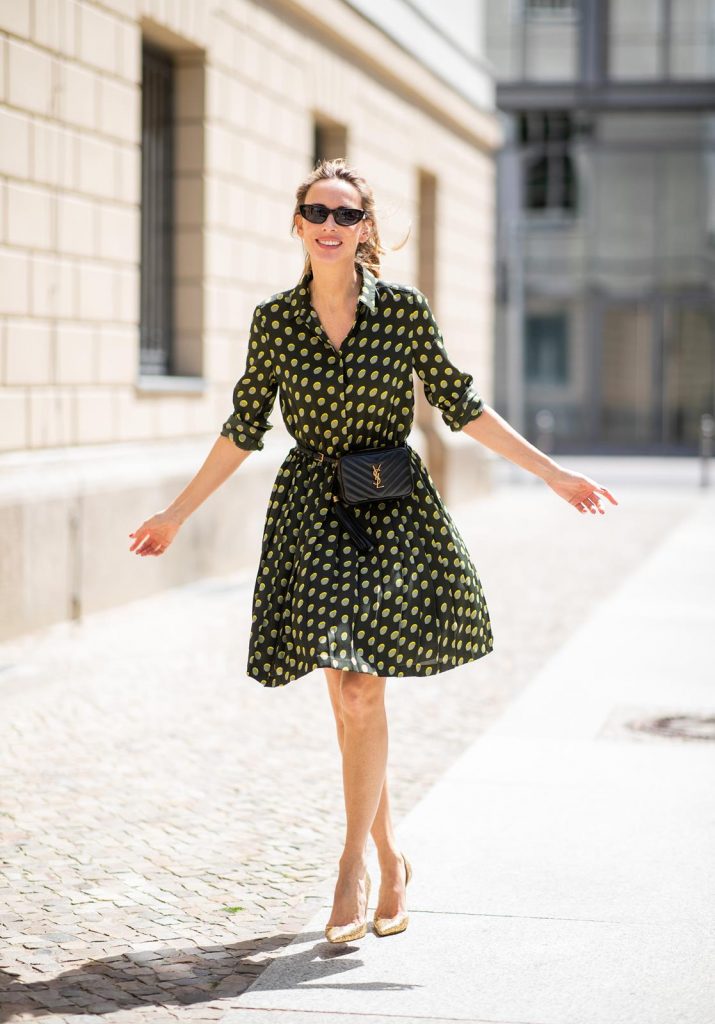 Steffen Schraut, Saint Laurent, Christian Louboutin, State Optical Co.  Alexandra Lapp is seen in a Waist Belt Bag Look wearing a knee length dark green dress with green and yellow dots from Steffen Schraut, the Lou Belt Bag in black by Saint Laurent, the golden Iriza glitter pumps by Christian Louboutin and two tone sunglasses from State x Cotw in black white on July 13, 2018 in Berlin, Germany.