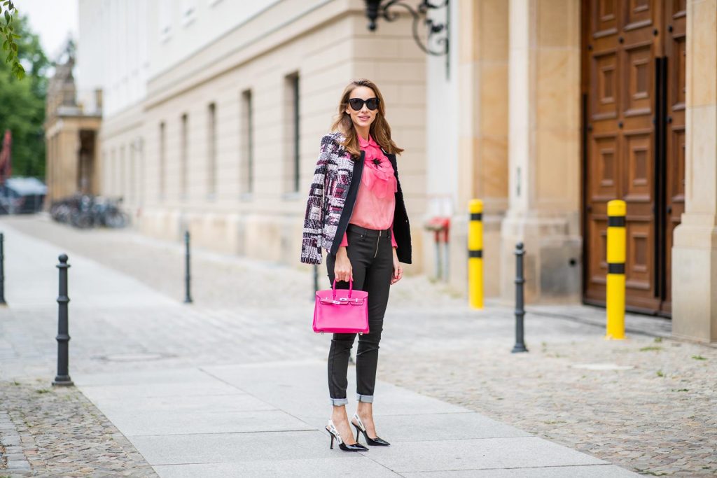 Alexandra Lapp in Birkin Bag Mini Look wearing a short checked colorful jacket with zipper from Airfield, transparent pink blouse with a big flower around the neck from Gucci, black Jeggins by Airfield, Dior slingback pumps in black with a J adior ribbon, a pink mini Birkin bag from Hermes, black Celine sunglasses and IWC watch during the Berlin Fashion Week July 2018 on July 6, 2018 in Berlin, Germany.