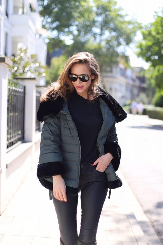 Airfield, SET, James Perse, Saint Laurent, Hermès, Céline Model and Blogger Alexandra Lapp in a Faux Fur Jacket Look wearing a black down jacket with faux fur by Airfield, black leather pants by SET, black T-Shirt by James Perse, dark green leather overknee boots by Saint Laurent, black Kelly bag by Hermès and black Audrey sunglasses from Céline.