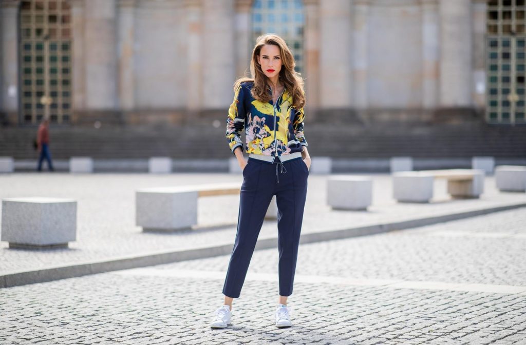 Alexandra Lapp in a Floral Jacket | Yellow Coat Look is seen wearing a blouson jacket with floral print, blue drawstring pants and a bright yellow duffle coat with a yellow fur hood from Airfield, Céline sunglasses in black, white Stan Smith Adidas sneakers with green details during the Berlin Fashion Week July 2018 on July 6, 2018 in Berlin, Germany.