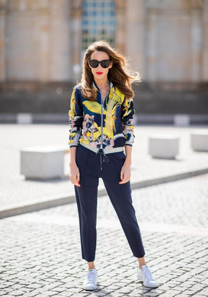 Alexandra Lapp in a Floral Jacket | Yellow Coat Look is seen wearing a blouson jacket with floral print, blue drawstring pants and a bright yellow duffle coat with a yellow fur hood from Airfield, Céline sunglasses in black, white Stan Smith Adidas sneakers with green details during the Berlin Fashion Week July 2018 on July 6, 2018 in Berlin, Germany.