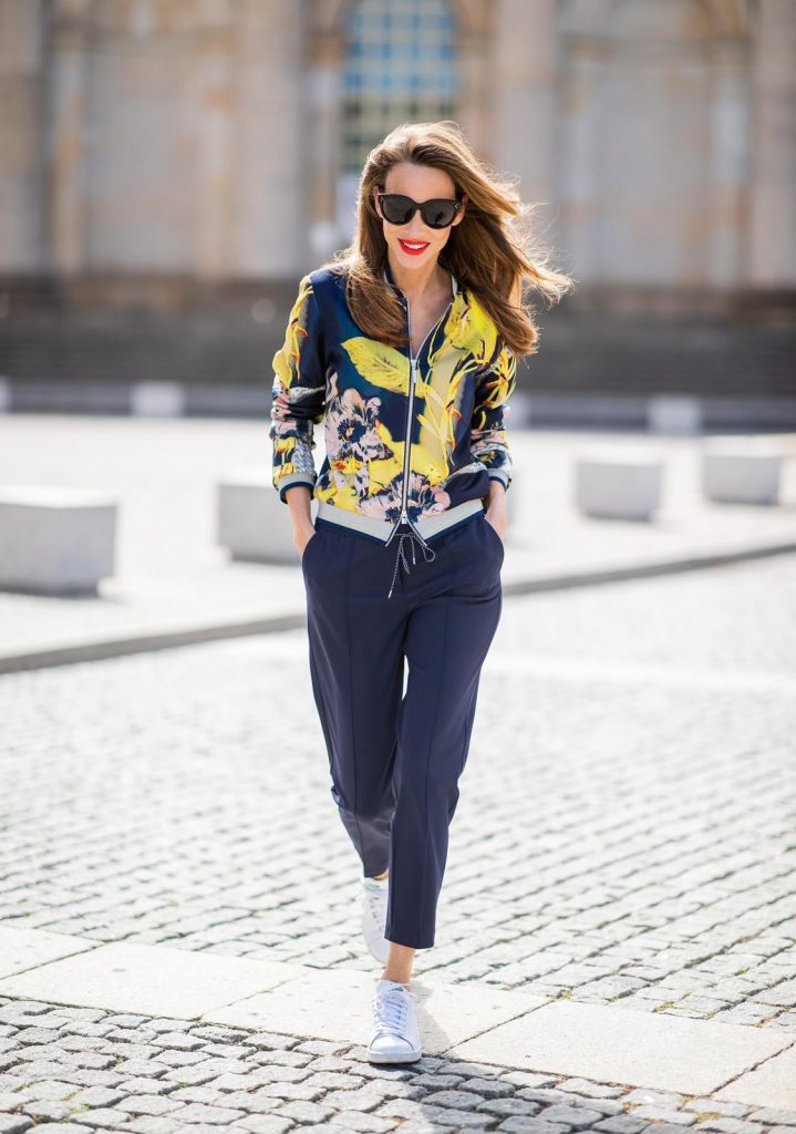 Alexandra Lapp in a Floral Jacket | Yellow Coat Look is seen wearing a blouson jacket with floral print, blue drawstring pants and a bright yellow duffle coat with a yellow fur hood from Airfield, Céline sunglasses in black, white Stan Smith Adidas sneakers with green details during the Berlin Fashion Week July 2018 on July 6, 2018 in Berlin, Germany.