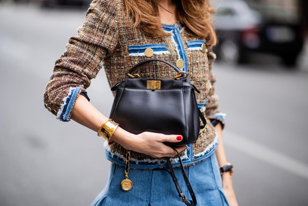 Alexandra Lapp in a Pleated Denim Skirt Look wearing a short tweed boucle jacket with denim from Steffen Schraut, a denim shirt from H&M, a denim pleated skirt from Balmain, vintage jewelry from Chanel, High Heel sandals 'Sandale Du Desert' in denim blue with a printed satin bow from Christian Louboutin and the Peekaboo Essentially Fendi handbag in black during the Berlin Fashion Week July 2018 on July 6, 2018 in Berlin, Germany.