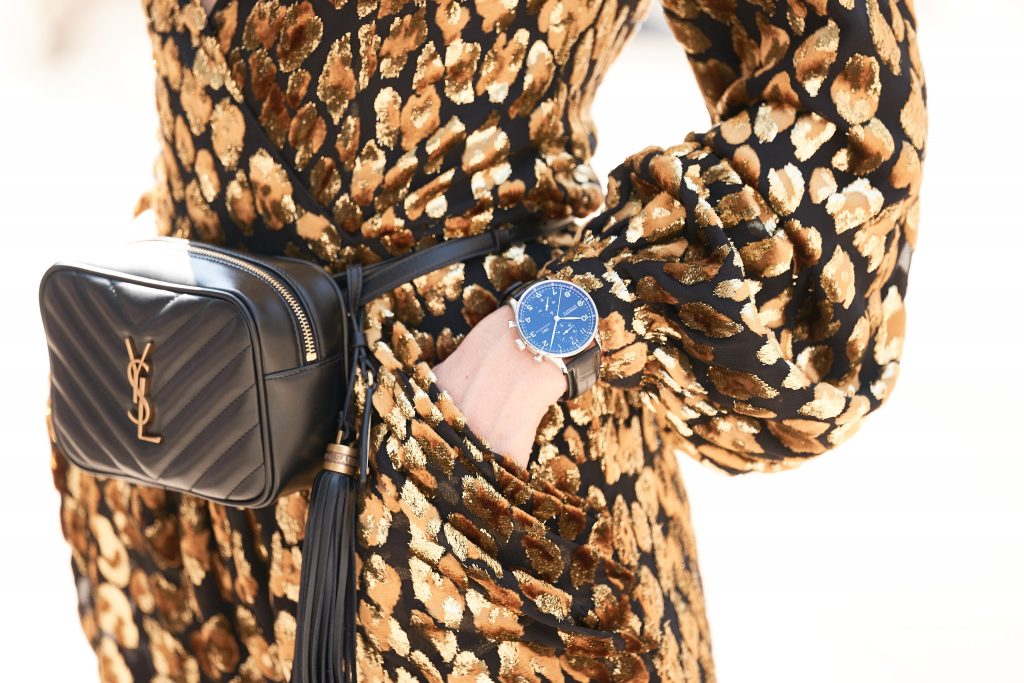 Model and Blogger Alexandra Lapp in an Animal Print Look wearing a leopard patterned jumpsuit in gold metallic by Maison Valentino, the Lou Camera Leather Crossbody Bag in black from Saint Laurent, Pigalle Follies 100 metallic crinkled leather Pumps in gold by Christian Louboutin and the Portugieser Chronograph watch by IWC.