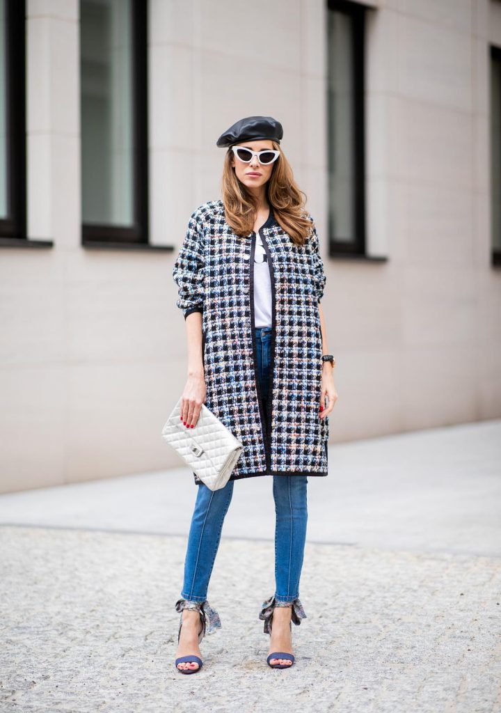 Alexandra Lapp wearing an oversized college jacket look with an oversized checkered college jacket from Steffen Schraut, stirrup denim pants from Steffen Schraut, a white V-neck t-shirt saying Vogue on the front from Your&Self, High Heel Sandals Sandale Du Desert in denim blue with a printed satin bow from Christian Louboutin, a silver Chanel handbag, white cat-eye sunglasses from YSL - Saint Laurent and Eugenia Kim leather basque Cher Barett on July 13, 2018 in Berlin, Germany.