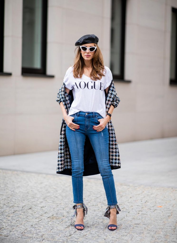 Alexandra Lapp wearing an oversized college jacket look with an oversized checkered college jacket from Steffen Schraut, stirrup denim pants from Steffen Schraut, a white V-neck t-shirt saying Vogue on the front from Your&Self, High Heel Sandals Sandale Du Desert in denim blue with a printed satin bow from Christian Louboutin, a silver Chanel handbag, white cat-eye sunglasses from YSL - Saint Laurent and Eugenia Kim leather basque Cher Barett on July 13, 2018 in Berlin, Germany.