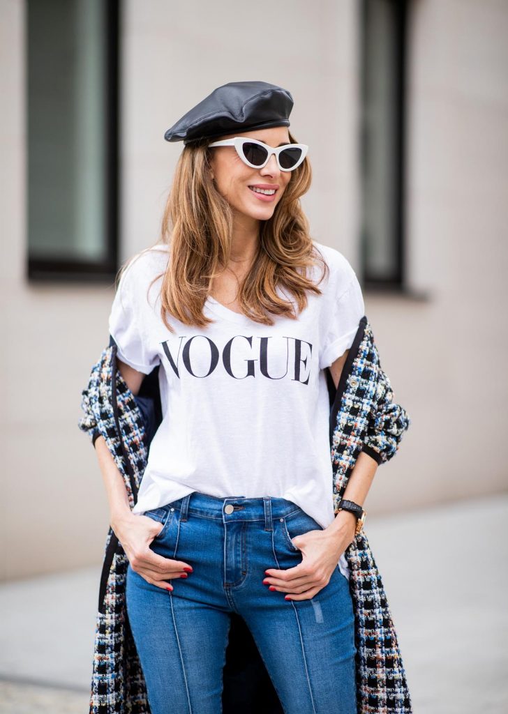 Alexandra Lapp wearing an oversized college jacket look with an oversized checkered college jacket from Steffen Schraut, stirrup denim pants from Steffen Schraut, a white V-neck t-shirt saying Vogue on the front from Your&Self, High Heel Sandals Sandale Du Desert in denim blue with a printed satin bow from Christian Louboutin, a silver Chanel handbag, white cat-eye sunglasses from YSL - Saint Laurent and Eugenia Kim leather basque Cher Barett on July 13, 2018 in Berlin, Germany.