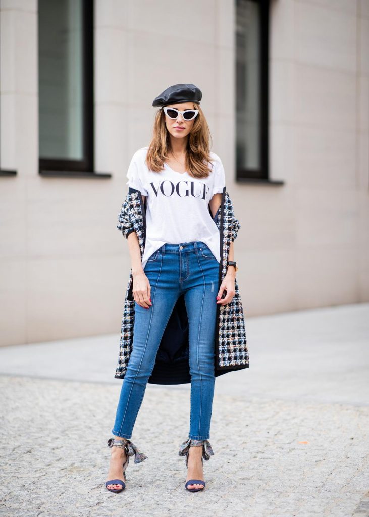 Alexandra Lapp wearing an oversized college jacket look with an oversized checkered college jacket from Steffen Schraut, stirrup denim pants from Steffen Schraut, a white V-neck t-shirt saying Vogue on the front from Your&Self, High Heel Sandals Sandale Du Desert in denim blue with a printed satin bow from Christian Louboutin, a silver Chanel handbag, white cat-eye sunglasses from YSL - Saint Laurent and Eugenia Kim leather basque Cher Barett on July 13, 2018 in Berlin, Germany.