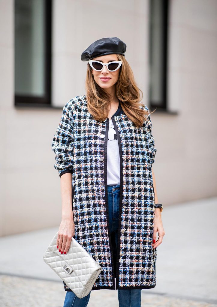 Alexandra Lapp wearing an oversized college jacket look with an oversized checkered college jacket from Steffen Schraut, stirrup denim pants from Steffen Schraut, a white V-neck t-shirt saying Vogue on the front from Your&Self, High Heel Sandals Sandale Du Desert in denim blue with a printed satin bow from Christian Louboutin, a silver Chanel handbag, white cat-eye sunglasses from YSL - Saint Laurent and Eugenia Kim leather basque Cher Barett on July 13, 2018 in Berlin, Germany.