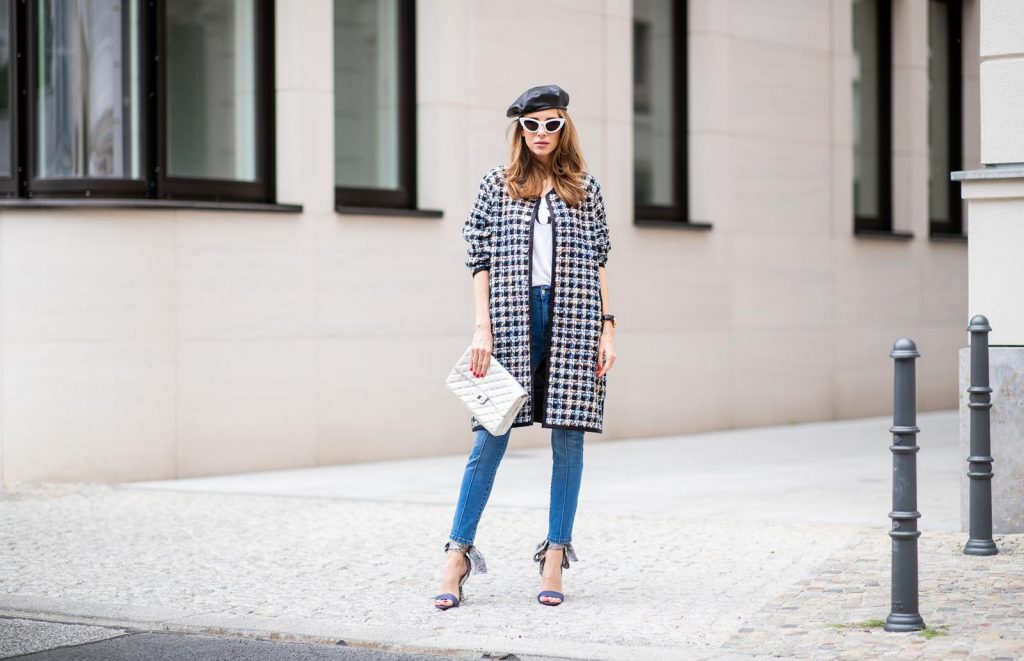 Alexandra Lapp wearing an oversized college jacket look with an oversized checkered college jacket from Steffen Schraut, stirrup denim pants from Steffen Schraut, a white V-neck t-shirt saying Vogue on the front from Your&Self, High Heel Sandals Sandale Du Desert in denim blue with a printed satin bow from Christian Louboutin, a silver Chanel handbag, white cat-eye sunglasses from YSL - Saint Laurent and Eugenia Kim leather basque Cher Barett on July 13, 2018 in Berlin, Germany.