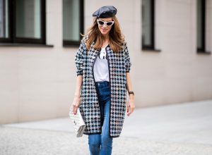 Alexandra Lapp wearing an oversized college jacket look with an oversized checkered college jacket from Steffen Schraut, stirrup denim pants from Steffen Schraut, a white V-neck t-shirt saying Vogue on the front from Your&Self, High Heel Sandals Sandale Du Desert in denim blue with a printed satin bow from Christian Louboutin, a silver Chanel handbag, white cat-eye sunglasses from YSL - Saint Laurent and Eugenia Kim leather basque Cher Barett on July 13, 2018 in Berlin, Germany.