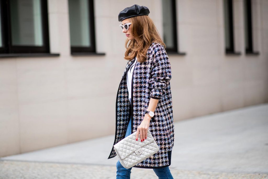 Alexandra Lapp wearing an oversized college jacket look with an oversized checkered college jacket from Steffen Schraut, stirrup denim pants from Steffen Schraut, a white V-neck t-shirt saying Vogue on the front from Your&Self, High Heel Sandals Sandale Du Desert in denim blue with a printed satin bow from Christian Louboutin, a silver Chanel handbag, white cat-eye sunglasses from YSL - Saint Laurent and Eugenia Kim leather basque Cher Barett on July 13, 2018 in Berlin, Germany.