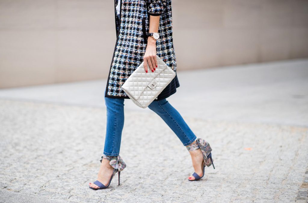 Alexandra Lapp wearing an oversized college jacket look with an oversized checkered college jacket from Steffen Schraut, stirrup denim pants from Steffen Schraut, a white V-neck t-shirt saying Vogue on the front from Your&Self, High Heel Sandals Sandale Du Desert in denim blue with a printed satin bow from Christian Louboutin, a silver Chanel handbag, white cat-eye sunglasses from YSL - Saint Laurent and Eugenia Kim leather basque Cher Barett on July 13, 2018 in Berlin, Germany.