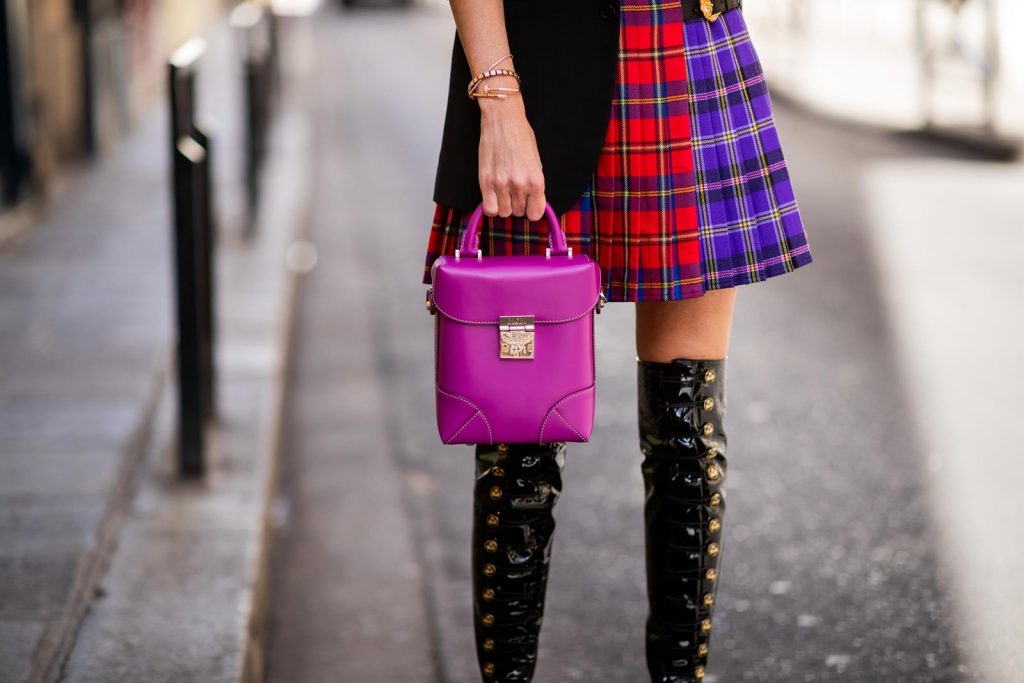 Alexandra Lapp in a Kilt Skirt Look wearing a long black boyfriend oversized blazer by Saint Laurent, a handmade Wodka Ogurez T-Shirt with a hand-painted print, a pleated patchwork tartan mini wool skirt from Versace, Frenchissima Alta Overknees in patent soft black leather by Christian Louboutin, Soft Berlin Crossbody Bag in Viva Lilac from MCM, vintage Chanel bakerboy cap in black and Neenah sunglasses from State Optical in black white is seen during Paris Fashion Week Womenswear Spring/Summer 2019 on September 29, 2018 in Paris, France.
