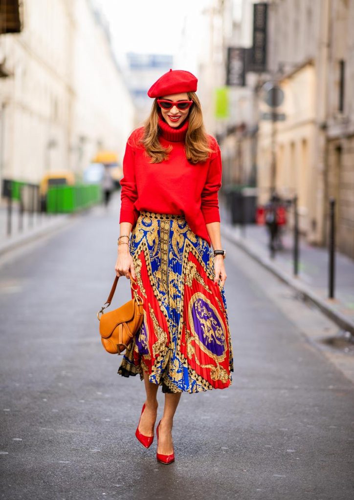 Versace, Falconeri, Dior, Gianvito Rossi, Zara, Céline Alexandra Lapp seen in a Versace Skirt Look wearing a pleated printed midi skirt from Versace, a long red cashmere turtle neck pullover from Falconeri, a vintage Dior saddle bag in cognac, red pumps from Gianvito Rossi, a beret cap in red from Zara, red cat-eye shaped sunglasses from Celine during Paris Fashion Week Womenswear Spring/Summer 2019 on September 29, 2018 in Paris, France.