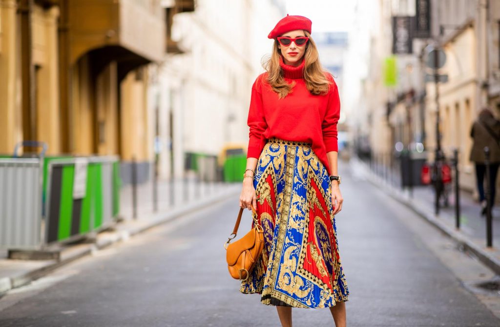Versace, Falconeri, Dior, Gianvito Rossi, Zara, Céline Alexandra Lapp seen in a Versace Skirt Look wearing a pleated printed midi skirt from Versace, a long red cashmere turtle neck pullover from Falconeri, a vintage Dior saddle bag in cognac, red pumps from Gianvito Rossi, a beret cap in red from Zara, red cat-eye shaped sunglasses from Celine during Paris Fashion Week Womenswear Spring/Summer 2019 on September 29, 2018 in Paris, France.