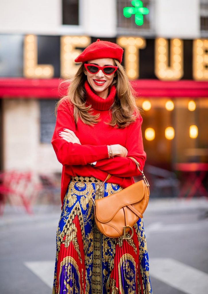 Versace, Falconeri, Dior, Gianvito Rossi, Zara, Céline Alexandra Lapp seen in a Versace Skirt Look wearing a pleated printed midi skirt from Versace, a long red cashmere turtle neck pullover from Falconeri, a vintage Dior saddle bag in cognac, red pumps from Gianvito Rossi, a beret cap in red from Zara, red cat-eye shaped sunglasses from Celine during Paris Fashion Week Womenswear Spring/Summer 2019 on September 29, 2018 in Paris, France.