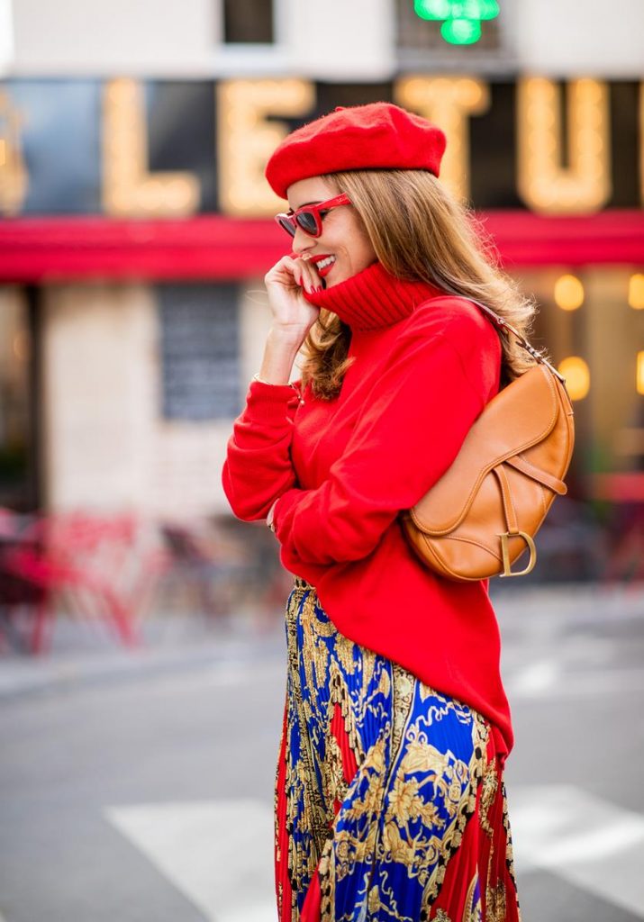 Versace, Falconeri, Dior, Gianvito Rossi, Zara, Céline Alexandra Lapp seen in a Versace Skirt Look wearing a pleated printed midi skirt from Versace, a long red cashmere turtle neck pullover from Falconeri, a vintage Dior saddle bag in cognac, red pumps from Gianvito Rossi, a beret cap in red from Zara, red cat-eye shaped sunglasses from Celine during Paris Fashion Week Womenswear Spring/Summer 2019 on September 29, 2018 in Paris, France.