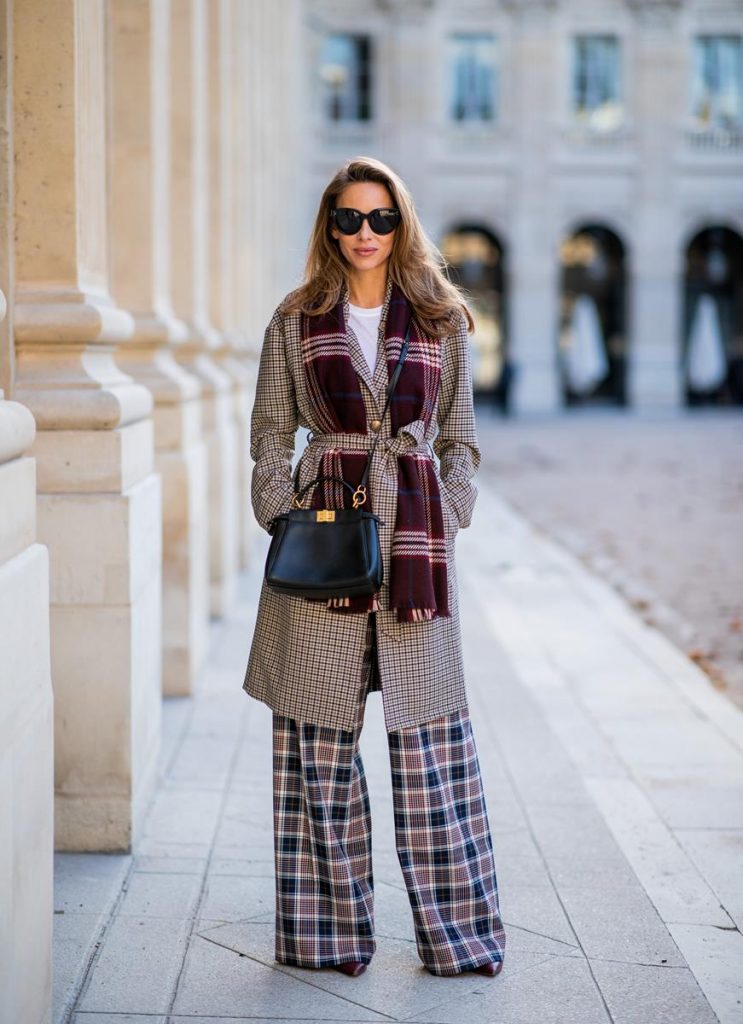 Alexandra Lapp in a Layered Look wearing a plaid oversized coat from SET fashion, a white T-Shirt from Vince, a Glenchek style scarf in dark red tones, wide plaid pants with a long leg in blue and brown tones from Tory Burch, boots in bordeaux from Gianvito Rossi and black Audrey sunglasses from Celine during Paris Fashion Week Womenswear Spring/Summer 2019 on September 27, 2018 in Paris, France.