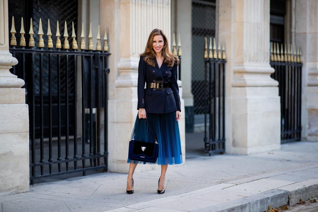 Alexandra Lapp in an All Blue Everything Look wearing a blue pleated skirt, navy striped blazer with belt and blue velvet bag all by Marc Cain, black heels from Christian Louboutin, a black lacquer waist belt by Dolce & Gabbana and black Audrey sunglasses by Céline seen during Paris Fashion Week Womenswear Spring/Summer 2019 on September 25, 2018 in Paris, France.