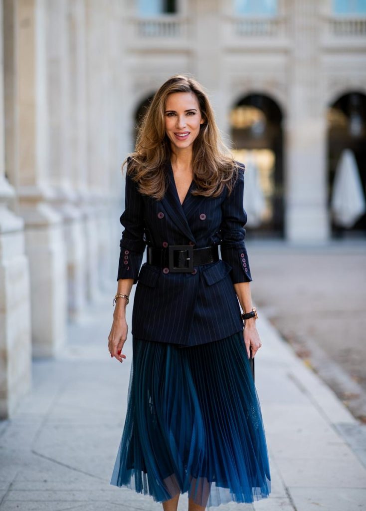 Alexandra Lapp in an All Blue Everything Look wearing a blue pleated skirt, navy striped blazer with belt and blue velvet bag all by Marc Cain, black heels from Christian Louboutin, a black lacquer waist belt by Dolce & Gabbana and black Audrey sunglasses by Céline seen during Paris Fashion Week Womenswear Spring/Summer 2019 on September 25, 2018 in Paris, France.
