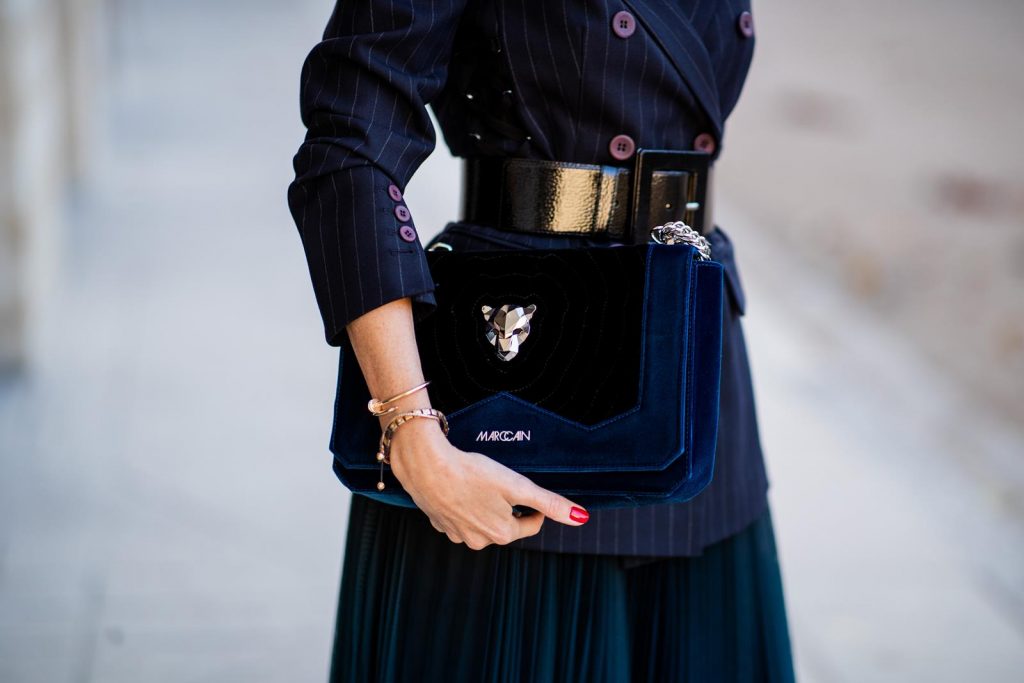 Alexandra Lapp in an All Blue Everything Look wearing a blue pleated skirt, navy striped blazer with belt and blue velvet bag all by Marc Cain, black heels from Christian Louboutin, a black lacquer waist belt by Dolce & Gabbana and black Audrey sunglasses by Céline seen during Paris Fashion Week Womenswear Spring/Summer 2019 on September 25, 2018 in Paris, France.
