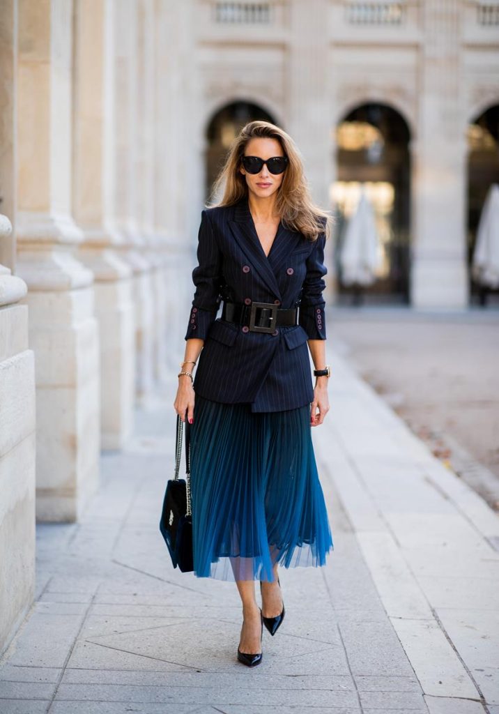 Alexandra Lapp in an All Blue Everything Look wearing a blue pleated skirt, navy striped blazer with belt and blue velvet bag all by Marc Cain, black heels from Christian Louboutin, a black lacquer waist belt by Dolce & Gabbana and black Audrey sunglasses by Céline seen during Paris Fashion Week Womenswear Spring/Summer 2019 on September 25, 2018 in Paris, France.