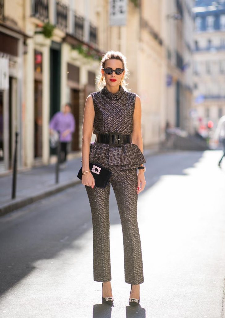 Alexandra Lapp in a Shiny Suit wearing a ruffled top with a collar and no arms from No21 in a shiny bronze and silver pattern with matching slim cut pants, black Flower Strass Buckle pumps by Roger Vivier, a lacquer waist belt from Dolce & Gabbana, black Soft Flowers Clutch by Roger Vivier and the Isabella black cat-eye shaped sunglasses from Illesteva.