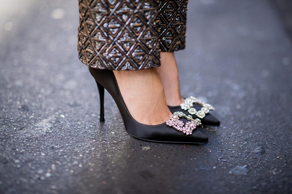 Alexandra Lapp in a Shiny Suit wearing a ruffled top with a collar and no arms from No21 in a shiny bronze and silver pattern with matching slim cut pants, black Flower Strass Buckle pumps by Roger Vivier, a lacquer waist belt from Dolce & Gabbana, black Soft Flowers Clutch by Roger Vivier and the Isabella black cat-eye shaped sunglasses from Illesteva.