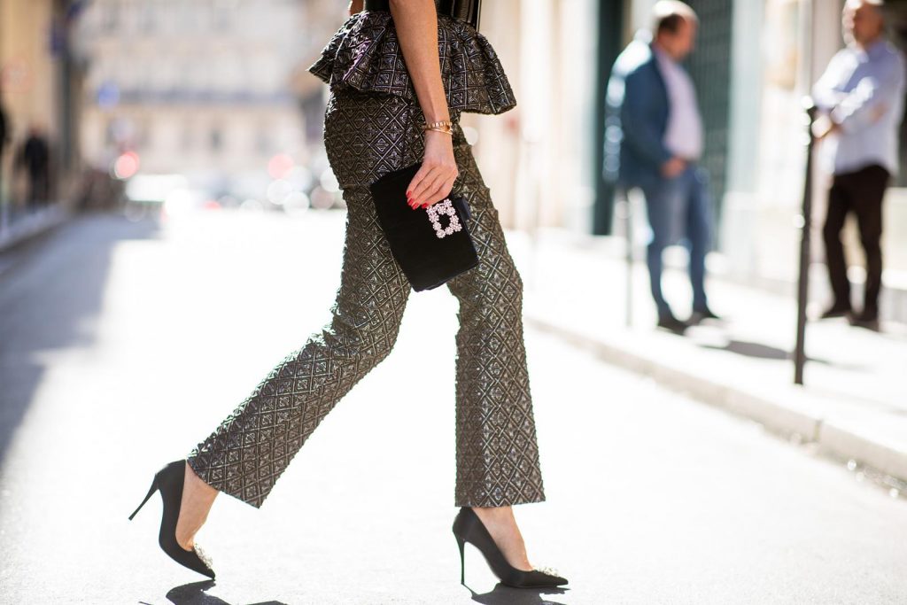 Alexandra Lapp in a Shiny Suit wearing a ruffled top with a collar and no arms from No21 in a shiny bronze and silver pattern with matching slim cut pants, black Flower Strass Buckle pumps by Roger Vivier, a lacquer waist belt from Dolce & Gabbana, black Soft Flowers Clutch by Roger Vivier and the Isabella black cat-eye shaped sunglasses from Illesteva.