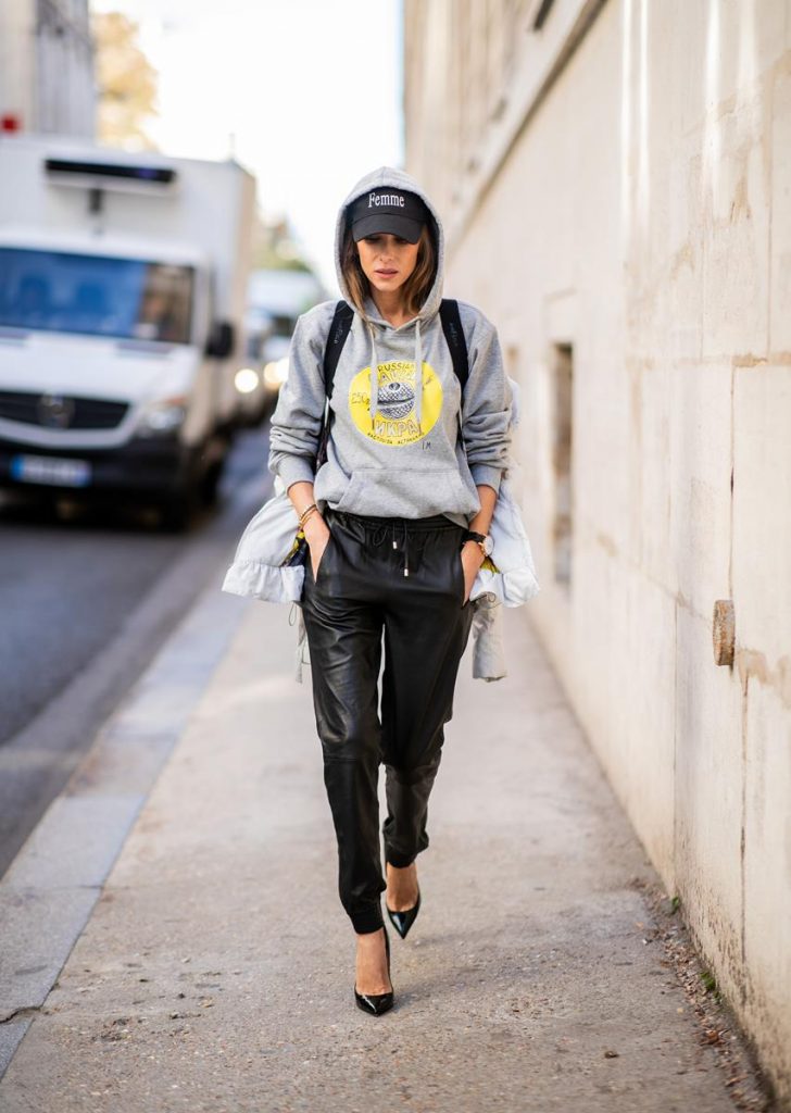 Alexandra Lapp in a Light Down Jacket Look wearing a light grey, fitted down jacket with inner carriers by Airfield, a handmade grey Hoodie with hand-painted print by Wodka Ogurez, black leather pants by SET, black Femme baseball cap from Balenciaga and black patent leather pumps by Christian Louboutin during Paris Fashion Week Womenswear Spring/Summer 2019 on September 24, 2018 in Paris, France.