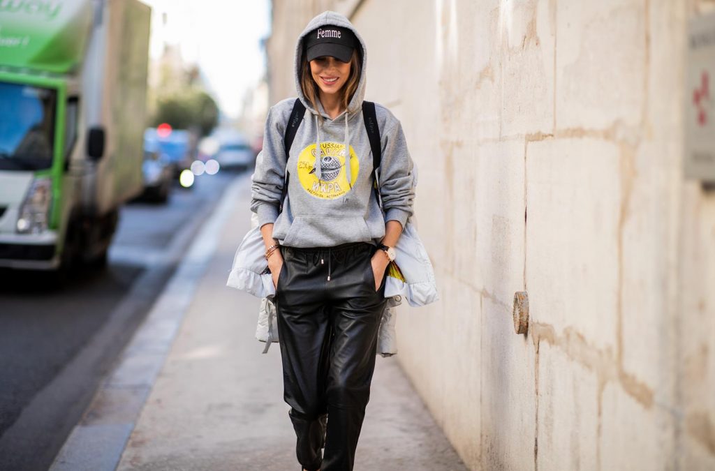 Alexandra Lapp in a Light Down Jacket Look wearing a light grey, fitted down jacket with inner carriers by Airfield, a handmade grey Hoodie with hand-painted print by Wodka Ogurez, black leather pants by SET, black Femme baseball cap from Balenciaga and black patent leather pumps by Christian Louboutin during Paris Fashion Week Womenswear Spring/Summer 2019 on September 24, 2018 in Paris, France.