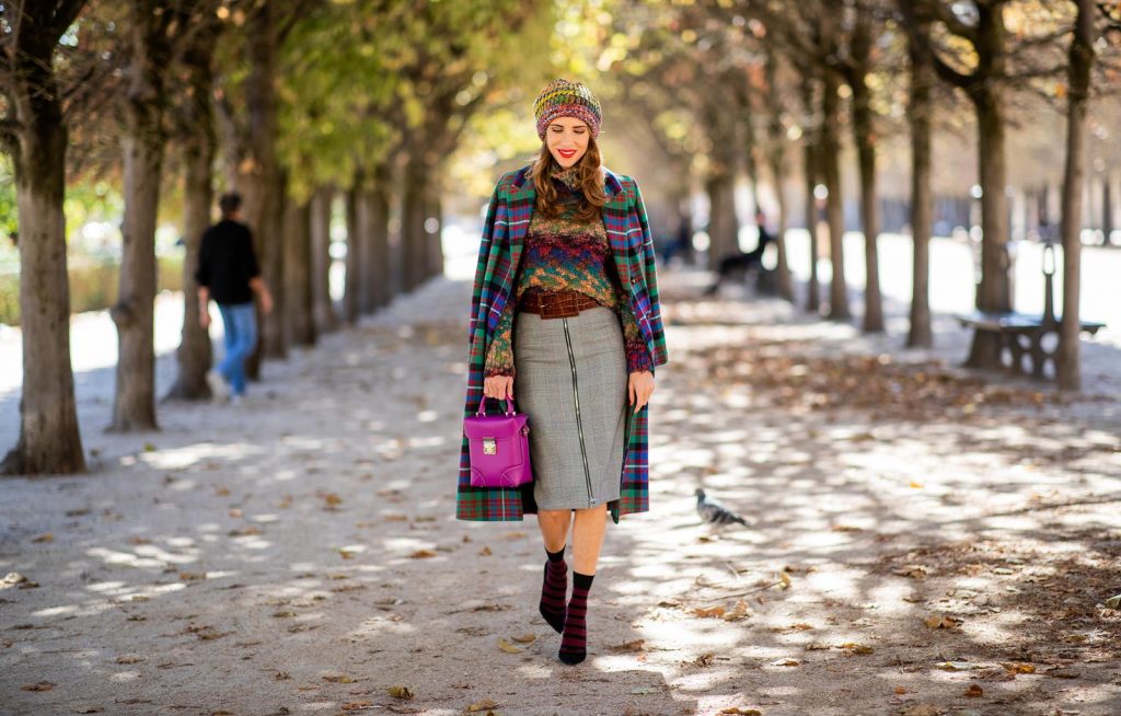 Alexandra Lapp in a Mixed Prints Look wearing a long multicolored plaid coat and a wool turtleneck multicolored sweater from Ouì, a black and white plaid slim cut skirt with a zipper up front from Ouì, a brown waist belt from Max Mara, black suede high heels from Christian Louboutin, the Soft Berlin Crossbody Bag in Viva Lilac from MCM, a multicolored wool hat from Missoni, purple black striped socks by H&M and the black Audrey sunglasses from Celine during Paris Fashion Week Womenswear Spring/Summer 2019 on September 25, 2018 in Paris, France.