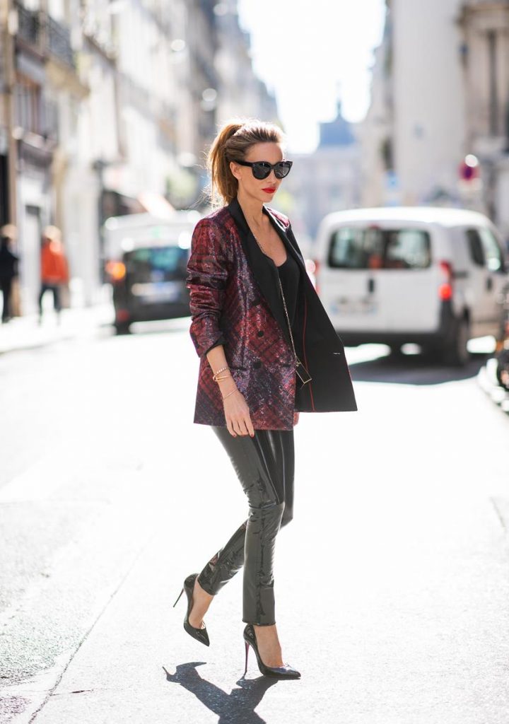 Rag & Bone, Tommy Hilfiger, Jadicted, Christian Louboutin, Roger Vivier, Céline Alexandra Lapp in a Faux Leather Pants Look wearing a long shiny sequin trimmed plaid blazer from Tommy Hilfiger, slim cut black vinyl pants from Rag & Bone, a black satin top from Jadicted, black lacquer pumps from Christian Louboutin, a Roger Vivier Stars Rivets leather cigarette case with a long golden chain and the black Audrey sunglasses from Celine during Paris Fashion Week Womenswear Spring/Summer 2019 on September 25, 2018 in Paris, France.