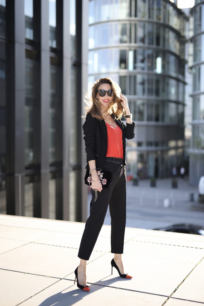 Alexandra Lapp in a Pop of Red Look wearing a stunning black blazer and pants combo from Airfield, mixed with a bright red silk top by Jadicted, an embroidered bag by Roger Vivier and a pair of Manolo Blahnik spiked heels.
