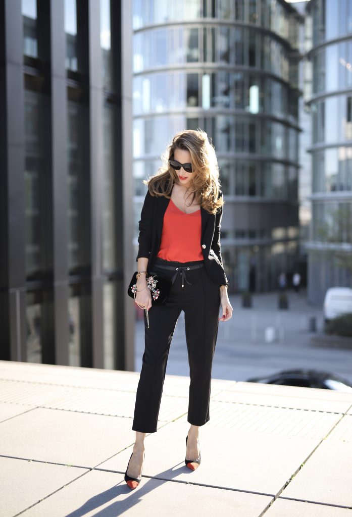 Alexandra Lapp in a Pop of Red Look wearing a stunning black blazer and pants combo from Airfield, mixed with a bright red silk top by Jadicted, an embroidered bag by Roger Vivier and a pair of Manolo Blahnik spiked heels.