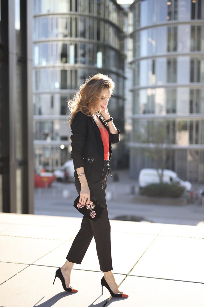 Alexandra Lapp in a Pop of Red Look wearing a stunning black blazer and pants combo from Airfield, mixed with a bright red silk top by Jadicted, an embroidered bag by Roger Vivier and a pair of Manolo Blahnik spiked heels.
