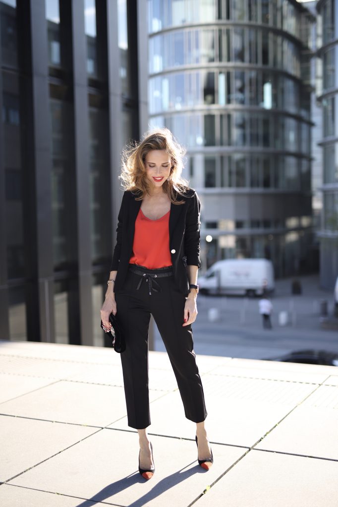 Alexandra Lapp in a Pop of Red Look wearing a stunning black blazer and pants combo from Airfield, mixed with a bright red silk top by Jadicted, an embroidered bag by Roger Vivier and a pair of Manolo Blahnik spiked heels.