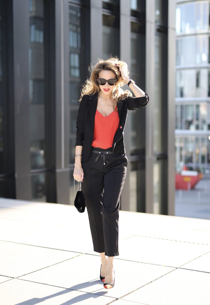 Alexandra Lapp in a Pop of Red Look wearing a stunning black blazer and pants combo from Airfield, mixed with a bright red silk top by Jadicted, an embroidered bag by Roger Vivier and a pair of Manolo Blahnik spiked heels.