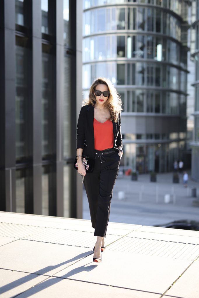 Alexandra Lapp in a Pop of Red Look wearing a stunning black blazer and pants combo from Airfield, mixed with a bright red silk top by Jadicted, an embroidered bag by Roger Vivier and a pair of Manolo Blahnik spiked heels.
