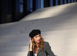 Alexandra Lapp in a Businesswoman Look wearing blazer and pants with polka dots in black white both from Airfield, red Jadicted silk top, black Lou leather belt bag by Saint Laurent, black patent leather pumps by Christian Louboutin, a black bakerboy cap by Dior and cat-eyed shaped vintage Gucci sunglasses with a white rim.