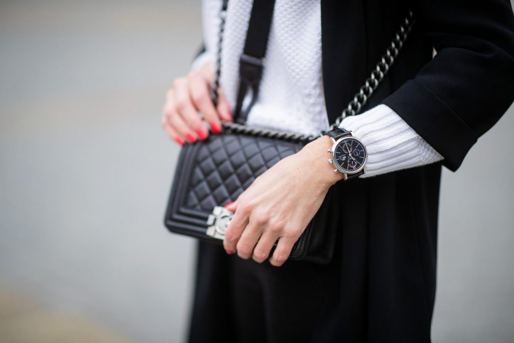 Alexandra Lapp in A Chanel Rain Boots look, wearing a soft long blazer by Steffen Schraut, over a white chunky knit sweater by H&M, black skinny pants with golden buttons by Veronica Beard, styled with Chanel logo suspenders and Chanel rain boots, the Chanel Le boy bag, a Chanel tweed baker boy cap and a transparent umbrella by Mirviory during the Berlin Fashion Week Autumn/Winter 2019 on January 15, 2019 in Berlin, Germany. (Photo by Christian Vierig/Getty Images)