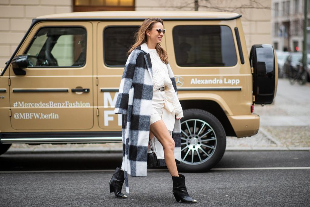 Alexandra Lapp in a Mercedes-Benz Fashion Look, in front of a Mercedes G500 wearing a black and white checked wool-blend coat from Ganni, off-white cable knit sweater from Maje, Isabel Marant ruffled skirt Nefly in off-white, embroided and silver buckled Tety belt and Lamsy ankle cowboy boots with silver tip from Isabel Marant, black Le boy bag from Chanel, Chanel brooch with Coco Chanel detail during the Berlin Fashion Week Autumn/Winter 2019 on January 16, 2019 in Berlin, Germany. (Photo by Christian Vierig/Getty Images)