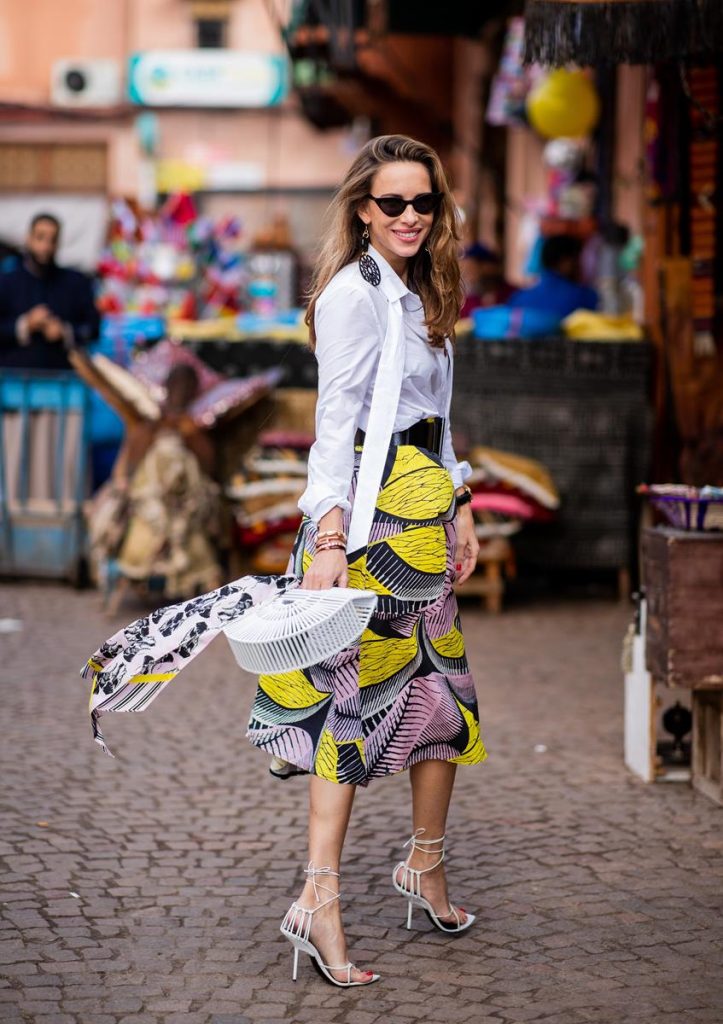Marc Cain Alexandra Lapp in a Le Riad look, wearing a flared skirt printed with pink, yellow and black patterns combined with a plain bowed white shirt, a matching silk printed scarf with elephants in the same colours and round big earrings in black all by Marc Cain, leather sandals in white, white bag and black cat-eyed shaped sunglasses on November 25, 2018 in Marrakech, Morocco. (Photo by Christian Vierig/Getty Images)