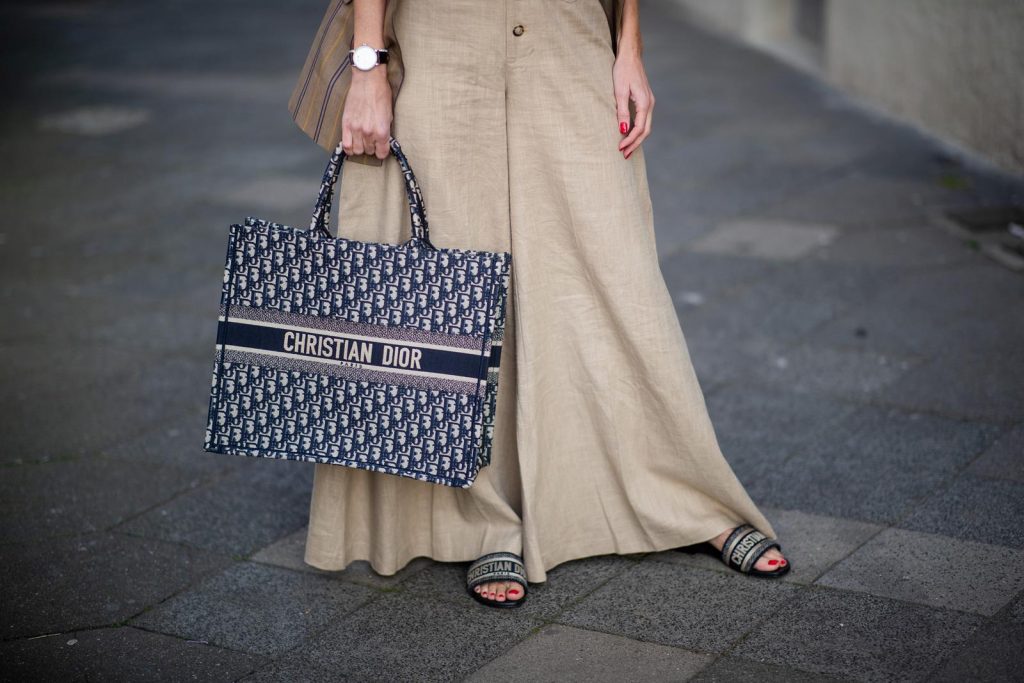 Alexandra Lapp in a Dior Book Tote Bag Look, wearing a beige brown long striped blazer from Zara, white tank top from H&M, waisted belt from Max Mara, high waisted wide leg pants from Staud, Dior Dway mules, Dior Book Tote Dior Oblique bag and a Dior foulard on a blue Borsalino hat on May 04, 2019 in Duesseldorf, Germany. (Photo by Christian Vierig/Getty Images)